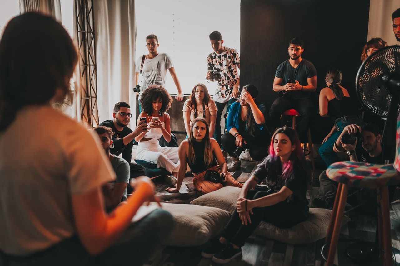 A group of multi-ethnic people gather around a speaker in a studio